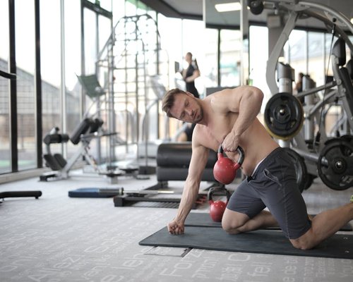 Person doing functional training with kettlebells in a bright modern gym