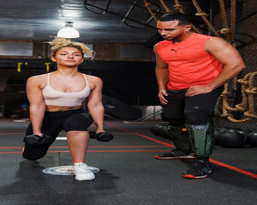 A friendly gym trainer helping a member correct their posture during a workout